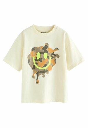 Cream-colored cotton t-shirt with short sleeves featuring a large camouflage smiley face and drips in neon green.