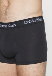 Boxer briefs in cotone nero con una ampia fascia elastica che presenta la scritta "Calvin Klein" in caratteri bianchi, texture liscia e design aderente.