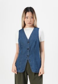 Denimvest med V-hals, har frontknapper, sidesømmer og en avslappet passform. Stoffet har en klassisk blå vask og en glatt tekstur.