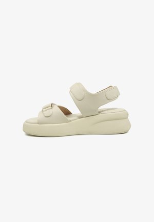 Sandale bej cu vârf deschis, talpă groasă și două bretele reglabile cu velcro, una peste degete și alta în jurul gleznei.