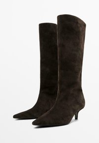 Stivali alti fino al ginocchio in suede marrone scuro con punta affusolata e tacco basso, caratterizzati da una texture liscia e elegante e un design aderente.