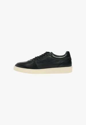 Basket basse en cuir noir avec lacets noirs et semelle en caoutchouc blanche, vue de profil extérieur sur fond blanc.