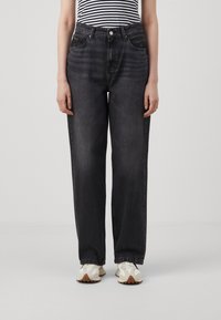 Dark gray high-waisted jeans with a loose fit, five-pocket design, and subtle fading, paired with white textured sneakers.