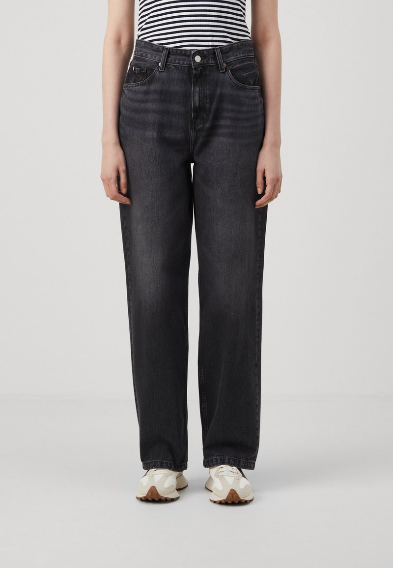 Dark gray high-waisted jeans with a loose fit, five-pocket design, and subtle fading, paired with white textured sneakers.