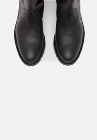 Černé kožené kotníkové boty s hladkým povrchem, kulatou špičkou a textura podešví. Obsahují minimální švy a bezšvový design svršku.