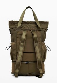 Sac à dos vert olive avec un dos rembourré, deux bretelles, deux poches latérales avec cordons de serrage et une poignée de transport sur le dessus, vu de dos.
