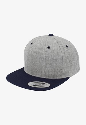 Casquette snapback grise avec un corps texturé et une visière en bleu marine uni. Présente un bouton noir sur le dessus et des œillets de ventilation. Étiquette sur la visière.