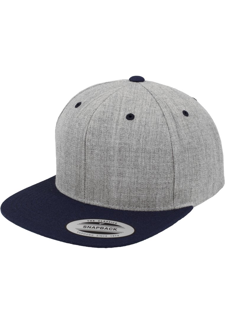 Grå snapback-cap med en teksturert kropp og en solid marineblå skygge. Har en svart knapp på toppen og ventilasjonslufter. Merke på skyggen.