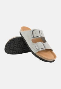 Gray suede sandals with two adjustable metal buckles, cork footbed, and textured black rubber outsole. Open-toe design with cutouts.