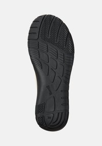 Semelle de chaussure en caoutchouc noir avec motifs de grip texturés, sections surélevées et indication de taille "38" embossée. Bords lisses et design flexible.