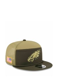 Grüne und beige Kappe mit flachem Schirm, auf der Vorderseite mit einem eingestickten Adler-Logo und auf der Seite mit einem Aufnäher der amerikanischen Flagge.