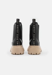 Černé kotníkové boty s lesklým povrchem, se silnou béžovou podrážkou. Černé textilní poutka s textem "PEPE JEANS" po stranách.