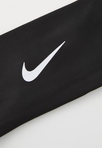 Must musta Nike käevarruka, millel on sile tekstuur, ja ülaosas on silmapaistev valge Nike swooshi logo.