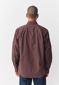 Camicia a quadri con motivo scozzese rosso, verde e bianco; colletto con polsini abbottonati; realizzata in tessuto leggero; maniche lunghe.