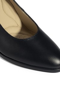 Chaussure en cuir noir avec un bout pointu, texture lisse et un petit talon. L'intérieur est doté d'une semelle rembourrée avec des détails de couture.