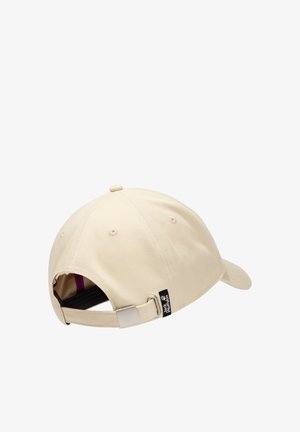 Casquette de baseball beige avec sangle réglable et boucle en métal, étiquette de marque visible à l'arrière, six œillets de ventilation et visière incurvée.
