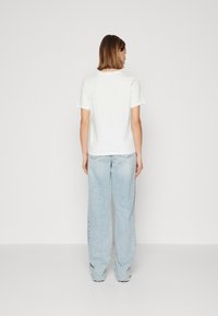 Weißes T-Shirt mit kurzen Ärmeln und rundem Halsausschnitt, kombiniert mit hellen, weiten Jeans. Glatte Textur, lässiges Design.