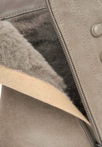 Szare zamszowe botki z miękką, puszystą podszewką i jasnobeżową podeszwą. Posiadają zamek błyskawiczny oraz zapięcie na guzik dla dodatkowego akcentu.