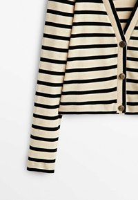 Cardigan beige à manches longues avec des rayures horizontales noires et trois boutons dorés décoratifs sur le devant.