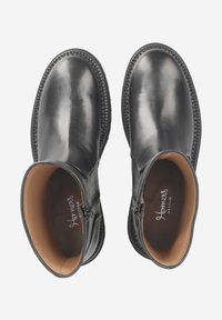 Black leather ankle boots with a smooth texture, round toe, side zippers, and beige lining, featuring a stitched sole for durability.