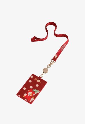 Czerwony smycz w białe grochy z logo "Cath Kidston", przymocowana do etui na karty z misiem w czerwonym kostiumie truskawki.