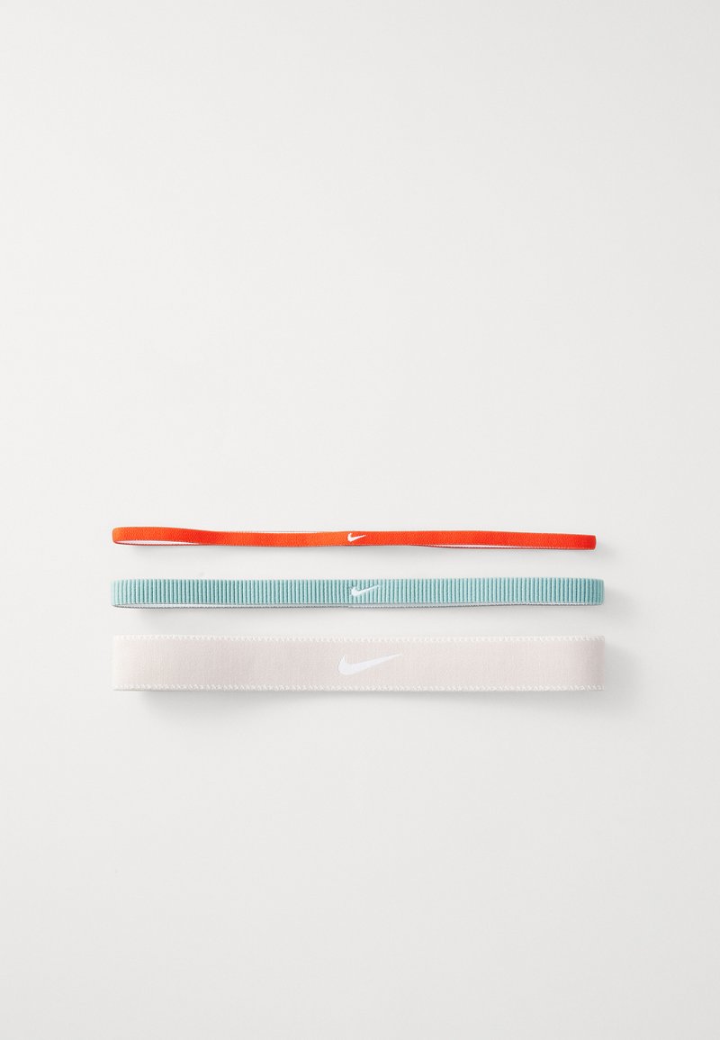 Sæt af tre hårbånd: et slankt orange bånd, et ribbet teal bånd og et glat hvidt bånd, alle med et subtilt Nike-logo.