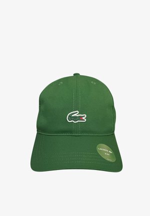 Cappellino da baseball verde con logo Lacoste a forma di coccodrillo sul davanti e adesivo rotondo sulla visiera, mostrato su sfondo bianco.