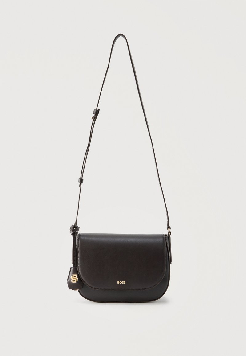 Μαύρη δερμάτινη τσάντα χιαστί με κλείσιμο καπακιού, ρυθμιζόμενο ιμάντα, μικρό χρυσό λογότυπο "BOSS" και προσαρτημένη ετικέτα με χρυσό έμβλημα "B".