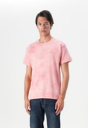 Pink short-sleeve T-shirt with a textured design and round neckline. Features a small logo on the chest. Paired with dark denim jeans.