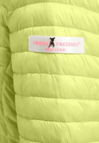 Lime green quilted jacket featuring horizontal stitching, a brand label with pink lettering, and a small black dog accent.