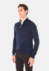 Maglione zip-up blu navy in morbido tessuto a maglia con colletto alto, polsini e orlo a coste, dotato di una piccola linguetta in pelle alla zip.