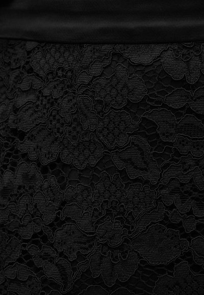 Tissu en dentelle noire avec des motifs floraux, des couches texturées et des détails complexes. Doublure douce et opaque visible en haut.