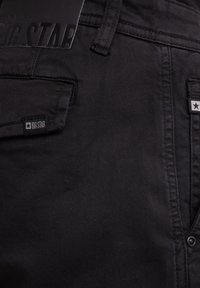 Sorte denim jeans med en struktureret finish, for- og baglommer samt et mærke med "BIG STAR" præget. Inkluderer stjerneaccenter.