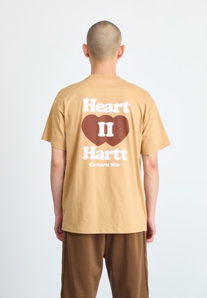 Brown cotton t-shirt featuring a large graphic on the back with the text "Heart II Hartt" and a heart design. Short sleeves and relaxed fit.