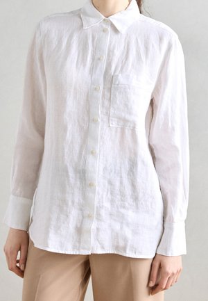 Wit linnen overhemden met knopen, een kraag, lange mouwen en een borstzak. Zachte textuur met een ontspannen pasvorm.