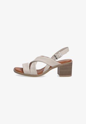 Sandale en cuir beige avec des lanières croisées, orteils ouverts et un talon bloc robuste. Dispose d'une boucle en métal argenté et d'un détail en bois texturé sur le talon.