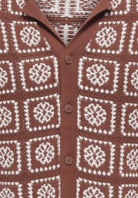 Cardigan marron tricoté avec un motif géométrique blanc, doté d'un col, de cinq boutons et de détails texturés.