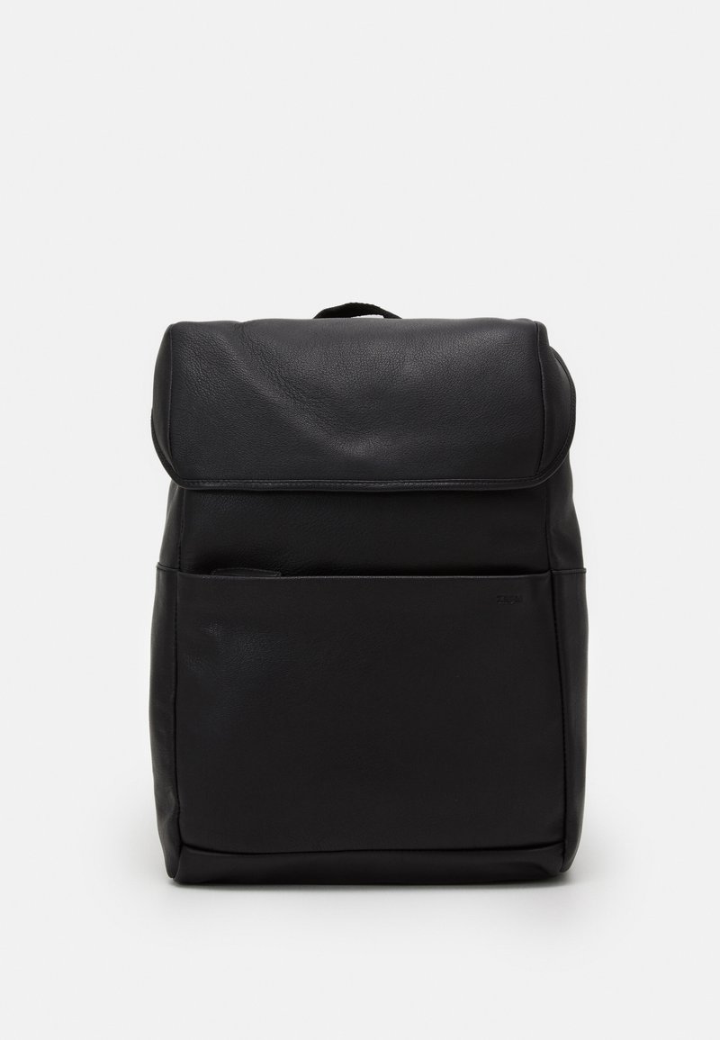 Sac à dos rectangulaire noir avec un rabat supérieur, une poche zippée à l'avant et une petite poignée de transport sur fond blanc.