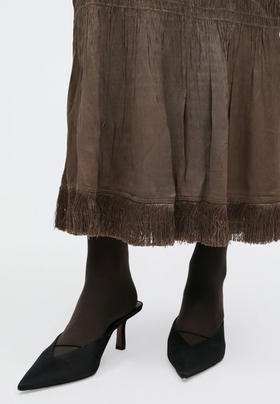 Barna texturált szoknya rojtos szegéllyel, fekete, hegyes orrú, magas sarkú klumpával párosítva. A klumpák nyitott hátúak és keresztbe átlapolt elülső részűek.