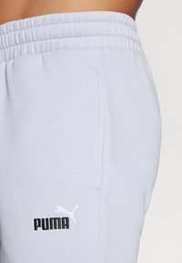 Light blue sweatpants made of cotton blend, featuring an elastic waistband and a side pocket. Black Puma logo on the lower leg.