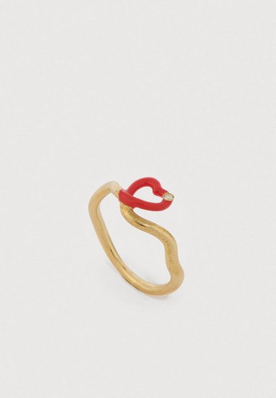 Prsteň zlatého tónu s vlnitým dizajnom, zdobený červeným srdiečkom a malým diamantovým detailom začleneným do tvaru srdca.