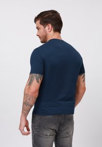 Camiseta de manga corta azul marino en una tela suave, diseño ajustado con corte recto, con cuello redondo y sin patrones ni acentos visibles.