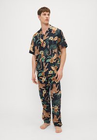 Set de pijamale cu mânecă scurtă, având un fond bleu marin, imprimeuri cu lei, flori tropicale și frunze. Material ușor, confortabil, cu pantaloni asortati.