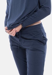 Navy long-sleeve top paired with matching joggers. The fabric is smooth with a relaxed fit, featuring an elastic waistband and drawstring.