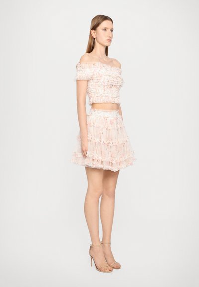 Top scurt fără umeri și fustă mini stratificată în culori pastel moi. Prezintă o textură volanată și un finisaj transparent cu modele florale delicate.