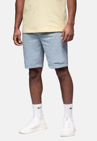 Shorts en coton bleu clair avec une texture lisse, présentant des coutures arrondies et un logo imprimé "OMBRE STREETSTYLE" en bas à droite.