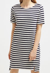 Abito a righe in navy e crema, maniche corte, scollatura tonda, lunghezza al ginocchio, con spacchi laterali e un tessuto testurizzato.