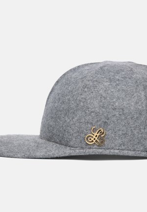 Casquette de baseball grise en feutre avec une visière incurvée et un petit logo ornemental doré sur le côté.