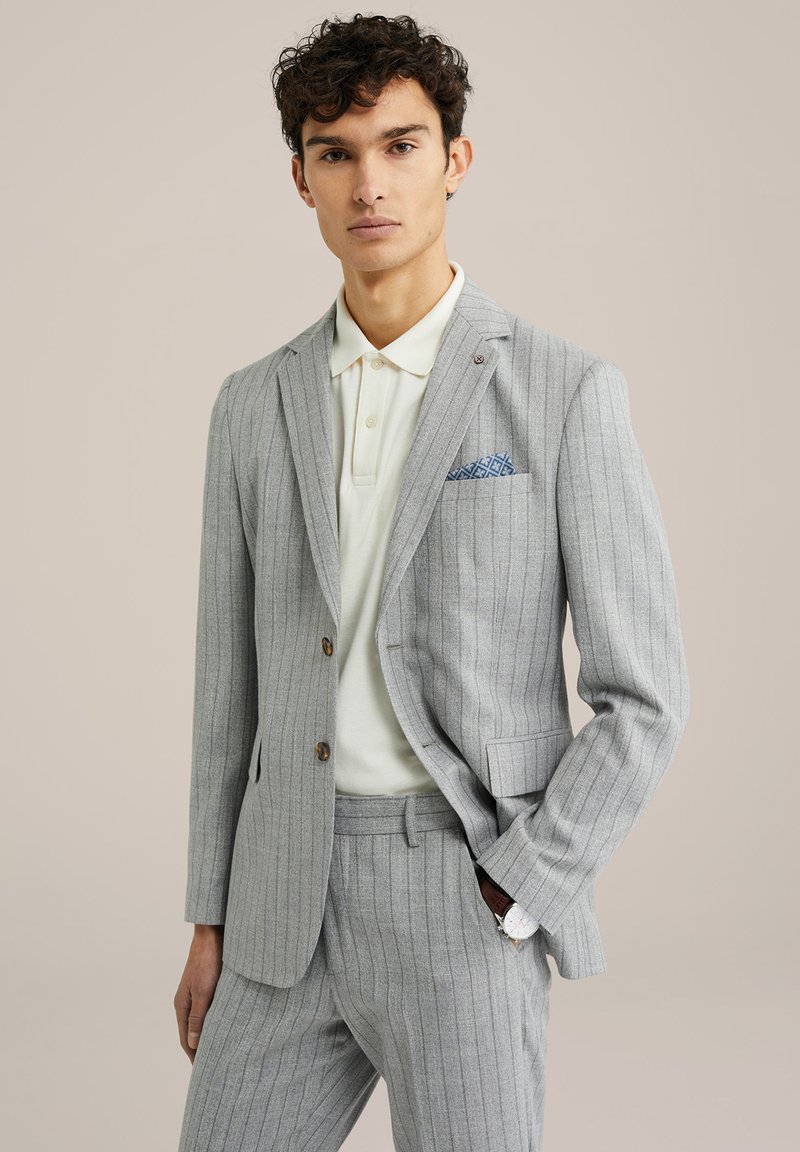 Traje gris a rayas finas hecho de tejido ligero, que cuenta con un blazer de dos botones, pantalones a juego y una camiseta polo blanca debajo.