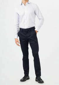 Gestreepte overhemden in lichtblauw en wit, gecombineerd met marineblauwe chinos en zwarte gepolijste schoenen, die een klassieke casual look uitstralen.